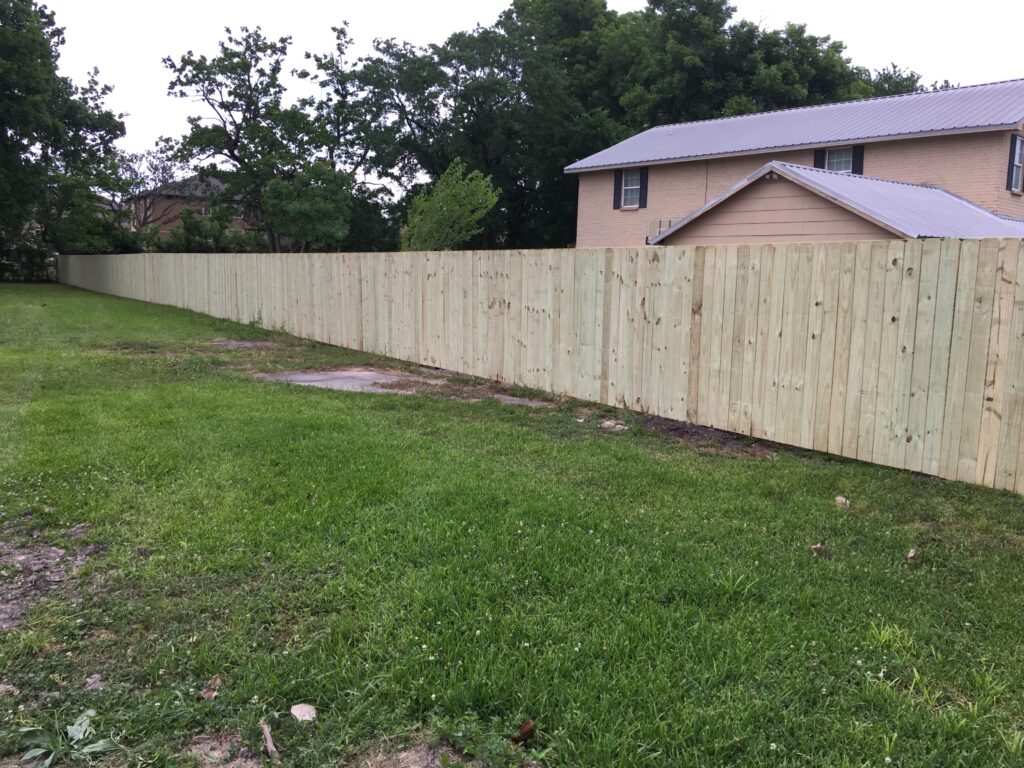 A fence that is made of wood and has grass around it.