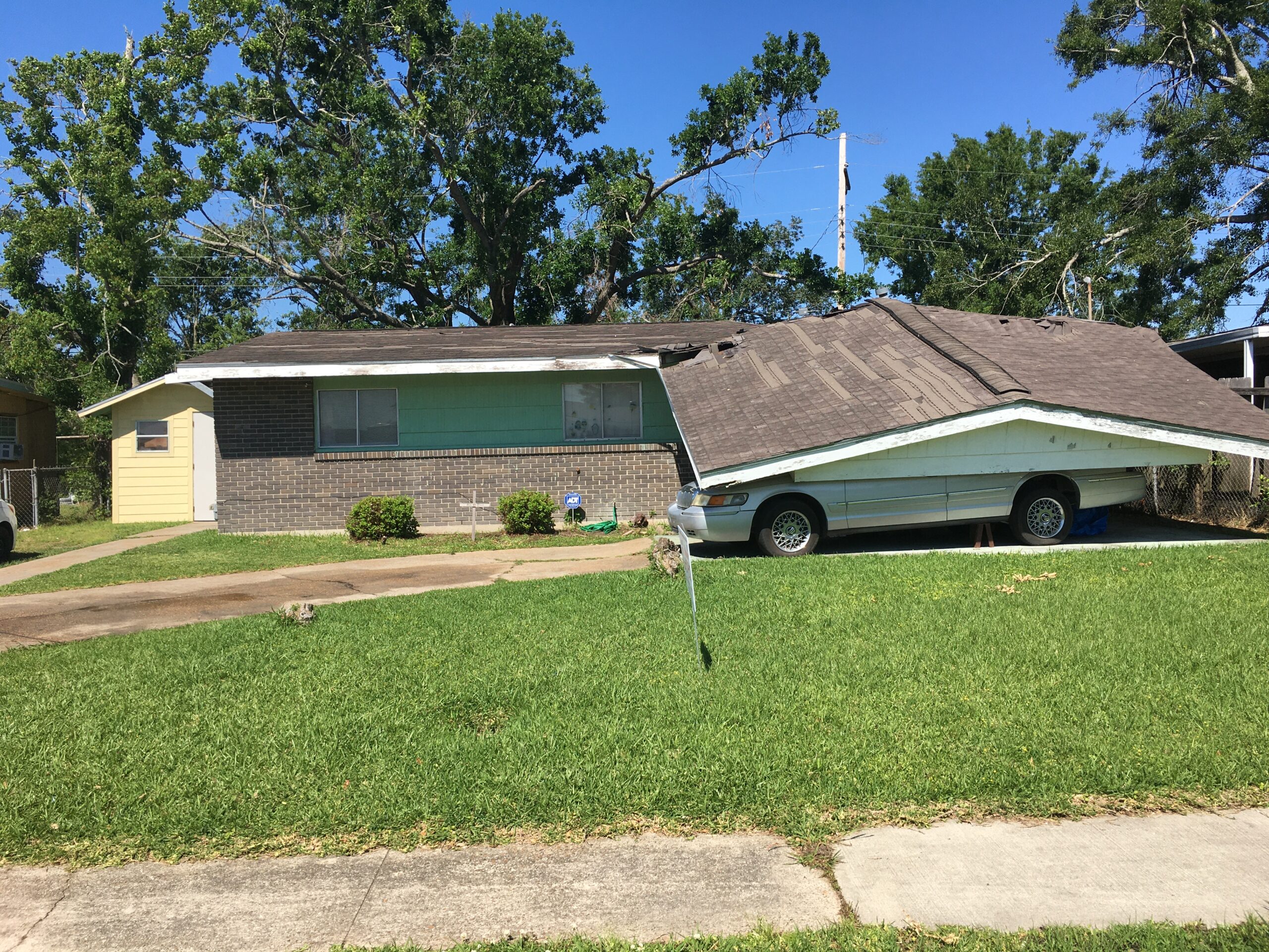 A car parked in front of a house that is broken.